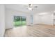 Spacious living room with ample natural light, sliding glass doors, ceiling fan, and wood grain flooring at 2651 Burri Ter, North Port, FL 34288