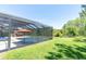 A screened in pool with seating and an umbrella for shade surrounded by green grass and trees on a sunny day at 3100 Barbour Trl, Odessa, FL 33556
