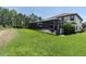 Lush green backyard featuring a screened-in pool with patio furniture and plenty of space for outdoor activities at 3100 Barbour Trl, Odessa, FL 33556