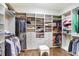 Spacious walk-in closet with custom shelving, drawers, and wood-look tile floors at 3243 Watermark Dr, Wesley Chapel, FL 33544