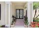 Elegant entryway showcasing double doors, stately columns, and colorful potted plants, creating a warm welcome at 3243 Watermark Dr, Wesley Chapel, FL 33544