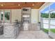 Outdoor kitchen boasts stone finishes, stainless steel appliances, and a wood plank ceiling at 3243 Watermark Dr, Wesley Chapel, FL 33544