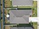 Aerial view of a house with a gray roof, screened in patio, landscaped backyard, and white fences at 36568 Garden Wall Way, Zephyrhills, FL 33541