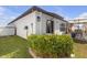 Well-maintained backyard featuring a manicured lawn, a modern white stucco home, and a covered outdoor dining area at 36568 Garden Wall Way, Zephyrhills, FL 33541