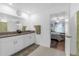 Bright bathroom featuring double sinks, granite counters, and a view to the connected bedroom with a ceiling fan at 36568 Garden Wall Way, Zephyrhills, FL 33541