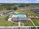 Aerial view of a community pool, clubhouse, playground, and surrounding green spaces with manicured landscaping at 36568 Garden Wall Way, Zephyrhills, FL 33541