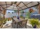 Inviting outdoor dining area with a shaded gazebo, surrounded by lush potted plants and colorful flowers for serene enjoyment at 36568 Garden Wall Way, Zephyrhills, FL 33541