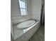 Luxurious soaking tub with marble-style tile surround, set beneath a bright, natural-light window at 37533 Teri Ct, Dade City, FL 33525