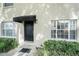 Townhouse entrance with a black awning and door framed by lush greenery and bright windows at 408 S Arrawana Ave # A4, Tampa, FL 33609