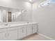 Bathroom with double sink vanity, framed mirror and neutral ceramic tile flooring at 4086 Polynesia Rd, North Port, FL 34288