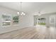 Spacious living room with hardwood floors, large windows, a modern chandelier, and patio access at 4086 Polynesia Rd, North Port, FL 34288