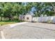 Exterior view of the house with gravel driveway and fenced in yard, surrounded by mature trees at 420 S Matanzas Ave, Tampa, FL 33609