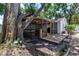 View of the screened in porch and deck in the backyard, surrounded by lush greenery and a mature tree at 420 S Matanzas Ave, Tampa, FL 33609