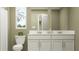 Bathroom featuring a dual sink vanity, mirror, toilet, and window for natural light, creating a functional and refreshing space at 5129 Benjamin Eric St, Zephyrhills, FL 33541