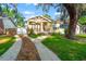 Charming yellow home with a large tree, manicured lawn, and welcoming front porch at 5804 N 9Th St, Tampa, FL 33604