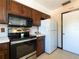 Kitchen features dark wood cabinets, stainless steel appliances and white refrigerator at 6251 Danbury St, Spring Hill, FL 34606