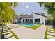 Modern backyard with a uniquely shaped pool, elegant lounge chairs, and pristine white tiling with grass accents at 7108 Pelican Island Dr, Tampa, FL 33634