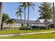 Stunning home featuring manicured landscaping, palm trees, and a modern design with a sleek, black roof at 7108 Pelican Island Dr, Tampa, FL 33634