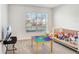 A cozy bedroom with a window, crib, and play area features a warm, inviting atmosphere at 7929 Sail Clover Ln, Zephyrhills, FL 33540