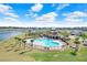 Community pool featuring a pool house, palm trees, lounge chairs, and a view of the surrounding neighborhood at 7929 Sail Clover Ln, Zephyrhills, FL 33540