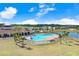 Community pool area with a clubhouse, palm trees, lounge chairs, and a lake backdrop at 7929 Sail Clover Ln, Zephyrhills, FL 33540