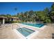 A pool area with a spa, lush landscaping, a building, lounge chairs, and sunny skies at 826 Glades Ne Ct, St Petersburg, FL 33702