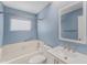 Updated blue bathroom features a tub with white tile surround, modern vanity, and bright natural light at 832 Fox Hills Dr, Sun City Center, FL 33573