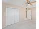 Neutral bedroom features a ceiling fan, carpeted floor, and a closet with white bi-fold doors at 832 Fox Hills Dr, Sun City Center, FL 33573