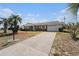 Well-maintained home featuring a brick facade, a spacious driveway, mature palm trees, and a neatly manicured lawn at 832 Fox Hills Dr, Sun City Center, FL 33573