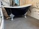 Close up of a black claw foot bathtub and luxurious grey penny tile flooring at 926 Eagle Ln, Apollo Beach, FL 33572
