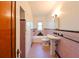 Pink and black tiled bathroom featuring a pedestal sink, tub, and diamond-patterned window at 101 22Nd N Ave, St Petersburg, FL 33704
