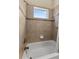 Bathroom featuring tile surround, a bathtub, a showerhead and a window for natural lighting at 10511 Mistflower Ln, Tampa, FL 33647
