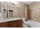 Well-lit bathroom with a single vanity, toilet, and tiled bathtub with shower at 10511 Mistflower Ln, Tampa, FL 33647