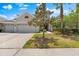 Charming home featuring a three-car garage, manicured landscaping, and a picturesque setting during the day at 10511 Mistflower Ln, Tampa, FL 33647