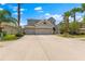Home featuring a three-car garage, well-maintained landscaping, and a spacious driveway under a blue sky at 10511 Mistflower Ln, Tampa, FL 33647