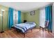 Cozy bedroom featuring hardwood floors, bright green walls, and blue curtains framing natural light from the windows at 1099 7Th Ne Ave, Largo, FL 33770