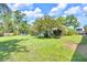 Spacious backyard featuring a lush lawn, mature trees, and view of the screened-in pool at 1220 Pinellas Point S Dr, St Petersburg, FL 33705