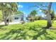 Lush backyard with mature trees, an outdoor fire pit with chairs, and a screened-in pool at 1220 Pinellas Point S Dr, St Petersburg, FL 33705