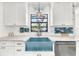Close up of kitchen sink with bright blue basin, white counters, and decor; a chef's delight at 1220 Pinellas Point S Dr, St Petersburg, FL 33705