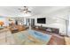 Spacious living room with hardwood floors, ceiling fan, television and view of dining and kitchen areas at 1220 Pinellas Point S Dr, St Petersburg, FL 33705