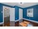 Bright, blue painted bedroom featuring hardwood floors, white trim, a window, and doors leading to other rooms at 1702 E Knollwood St, Tampa, FL 33610
