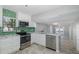 Updated kitchen with white cabinets, stainless steel appliances, and green backsplash at 1702 E Knollwood St, Tampa, FL 33610