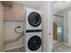 Laundry room area featuring a modern stacked washer and dryer, cabinet storage, and a bathroom at 1702 E Knollwood St, Tampa, FL 33610