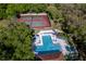 Aerial view of a community pool and tennis courts surrounded by mature trees and landscaping at 2627 2Nd Ct, Palm Harbor, FL 34684