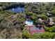 Aerial view featuring a pool and tennis court complex surrounded by lush trees at 2627 2Nd Ct, Palm Harbor, FL 34684