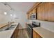 Well-lit kitchen offering stainless steel appliances, wood cabinetry, and a breakfast bar with sink at 2627 2Nd Ct, Palm Harbor, FL 34684