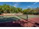 Tennis court with a net surrounded by trees on a sunny day at 2627 2Nd Ct, Palm Harbor, FL 34684