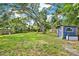 A backyard with a shed, mature shade tree, and a wood fence providing privacy at 511 San Jose Dr, Dunedin, FL 34698
