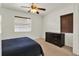 Cozy bedroom with a ceiling fan, brown blinds, carpeted floors, and a dark dresser against a white wall at 511 San Jose Dr, Dunedin, FL 34698