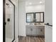 Modern bathroom featuring dual sinks, grey cabinets, tile flooring, and a glass door shower at 5133 Harbinger Rd, Spring Hill, FL 34608